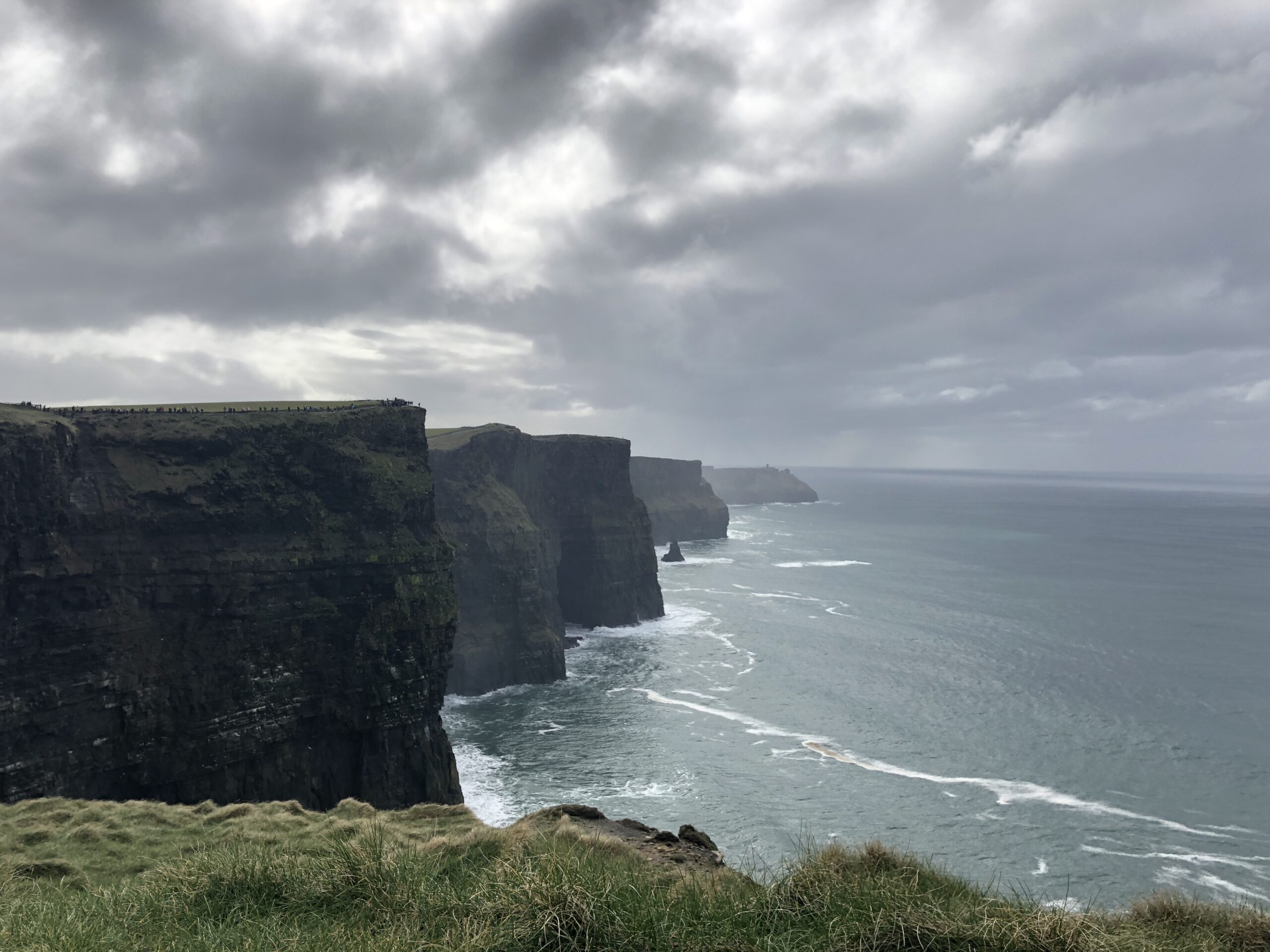 a photo of dramatic cliffs and ocean on a cloudy day at cliffs of moher in ireland