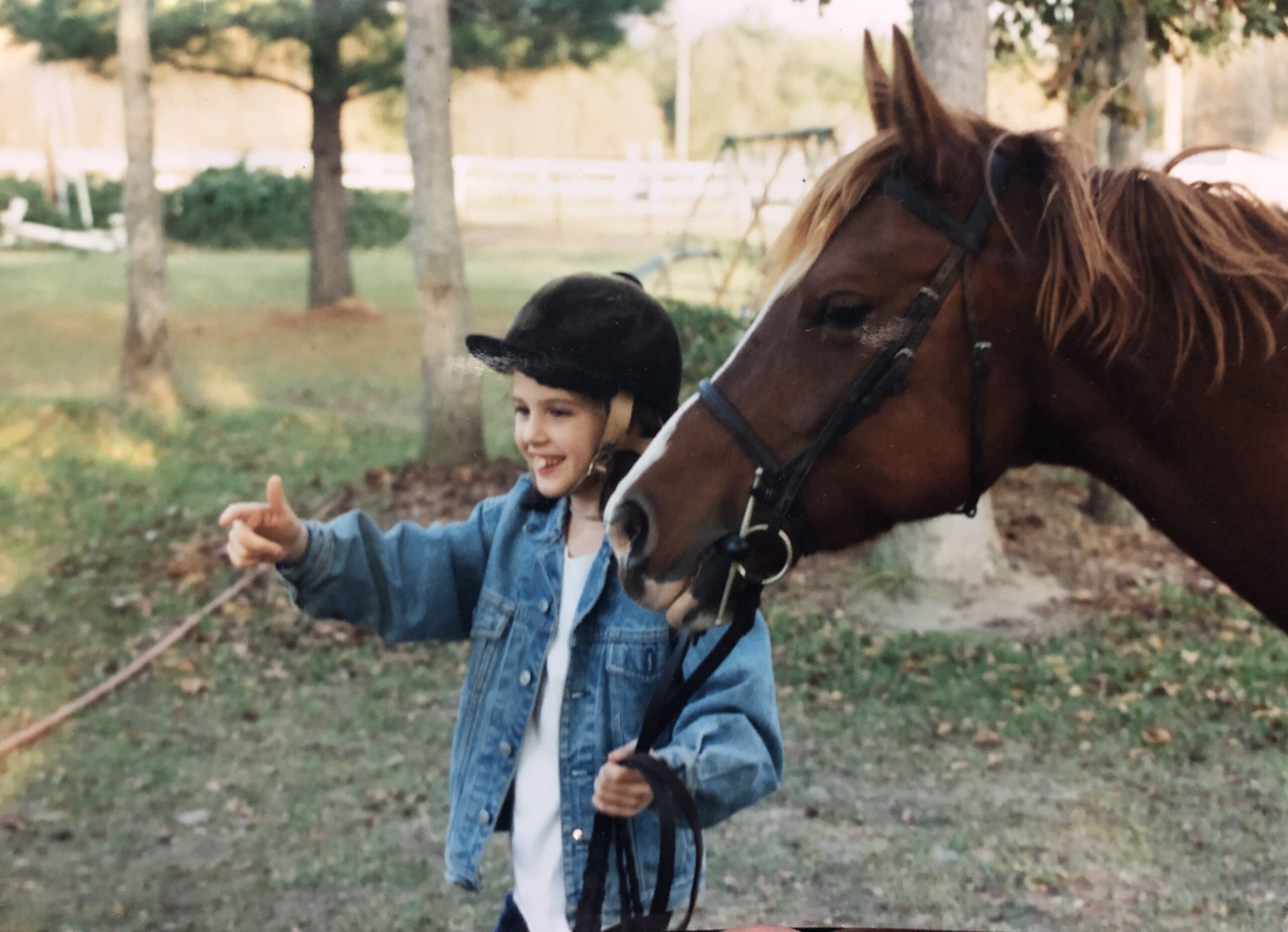 a young girl in a jean jacket leadinga chestnut pony